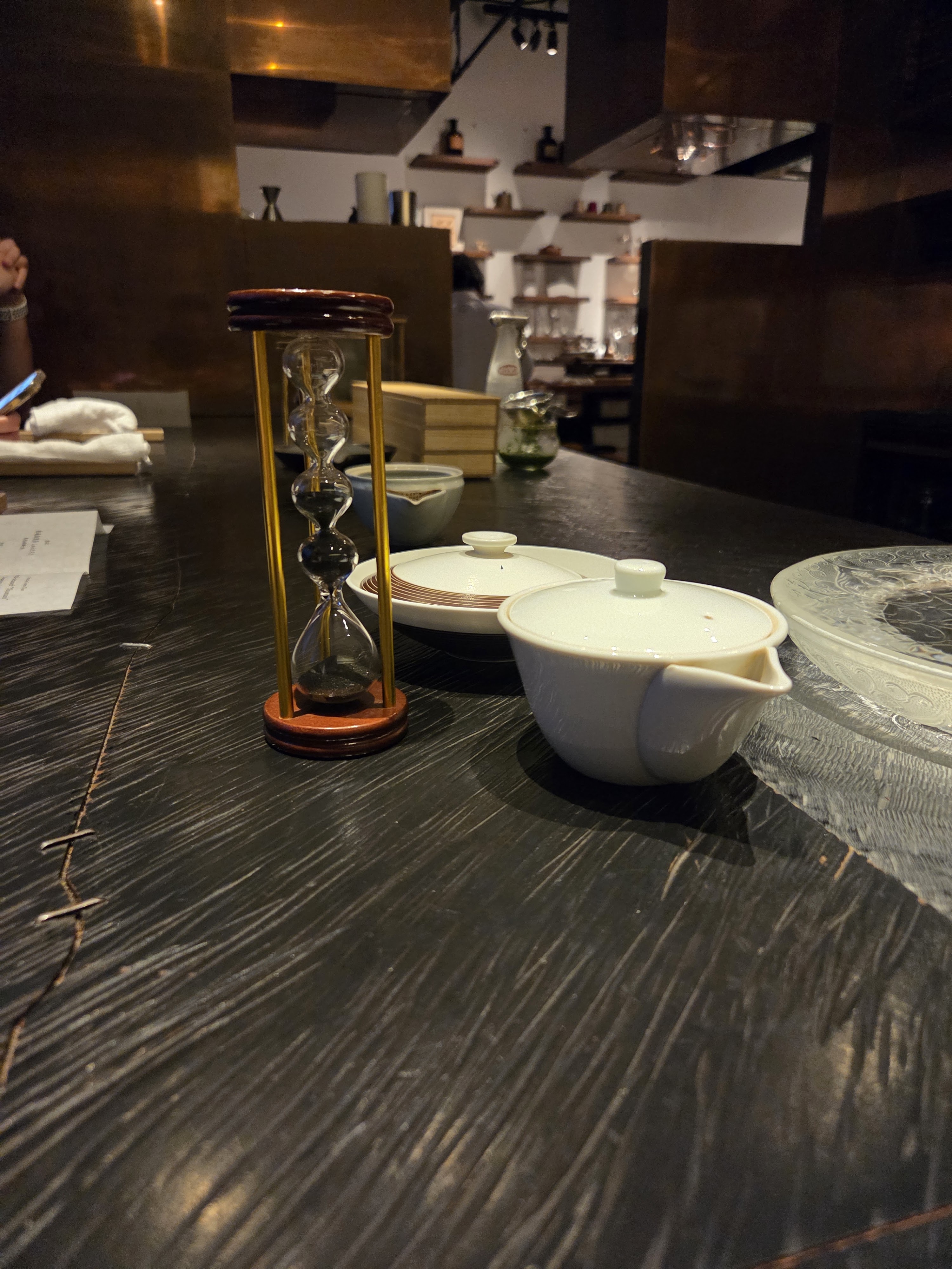 Brewing vessels and a multi-stage hourglass arranged on the tea counter